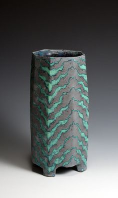 a green and gray vase sitting on top of a table