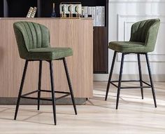 two green velvet bar stools in front of a bookcase and kitchen countertop