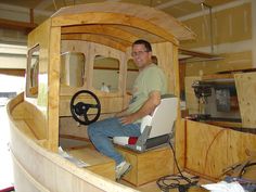 a man is sitting in the driver's seat of a wooden boat with steering wheel