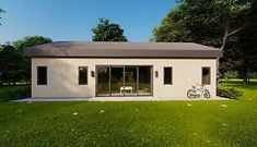 a small white house sitting in the middle of a lush green field with a bicycle parked next to it