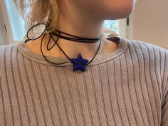 a woman wearing a necklace with a blue star on the front and black cord around her neck