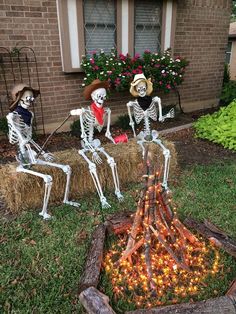 three skeletons sitting on hay bales in front of a house