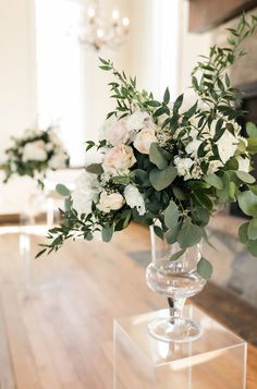 a vase filled with flowers sitting on top of a wooden table next to a fireplace