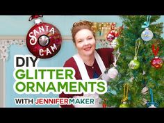 a woman standing next to a christmas tree in front of a sign that says diy glitter ornaments