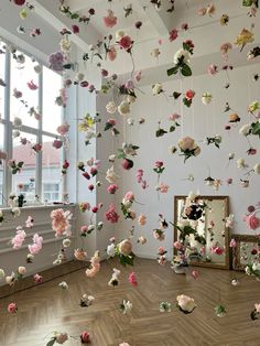 a room filled with lots of pink and white flowers hanging from the ceiling next to a mirror