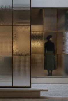 a man standing in front of a glass door with gold foil on it's side