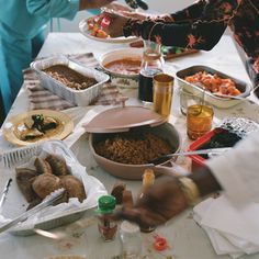 several people are serving themselves food at a table