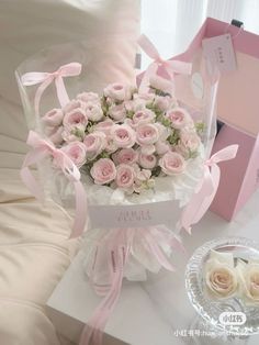 a bouquet of pink roses is sitting on a table next to a box of cookies