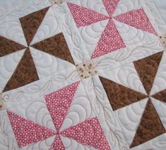 a quilted table topper with pink and brown designs on it's edges