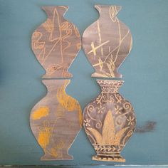 two decorative vases sitting side by side against a blue wall with gold paint on them