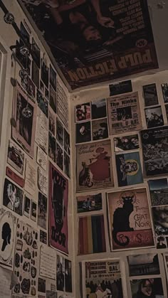 a wall covered in posters and pictures next to a toilet