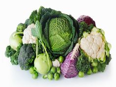 a pile of different types of vegetables on a white surface with green leaves and red cabbage