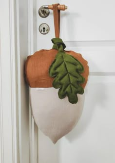 a door handle with a green and brown leaf hanging from it's side on a white door