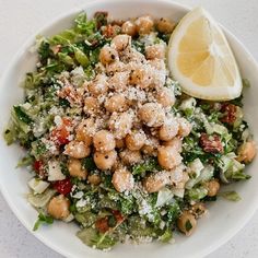 a white bowl filled with salad and lemon wedge