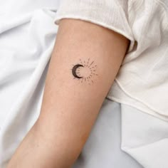 a woman's arm with a small sun and moon tattoo on the left forearm