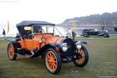 an orange and black car parked on top of a grass covered field