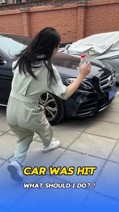 a woman in grey jumpsuit standing next to a black car with the words car was hit what should i do?