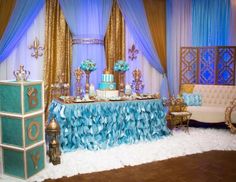 a table topped with a cake next to a couch and chair covered in blue ruffles