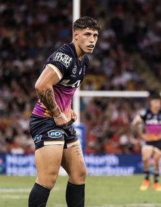 a rugby player standing on the field with his hands in his pockets and looking down