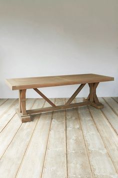 a wooden table sitting on top of a hard wood floor next to a white wall