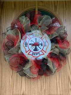 a fire department wreath with red and gold mesh around it on a wooden door frame