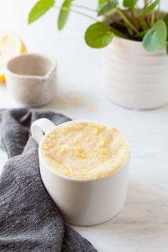 a cup of coffee sitting on top of a table next to a potted plant