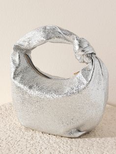 Give your winter accessories a chic update with Shiraleah’s Chrissy Metallic Velvet Top Handle Bag. This petite handbag is made from textured metallic PU giving its elegant silver color a trendy and unique shimmer. With its unique top handle silhouette featuring an elegant knot detail, it is the perfect accessory to add to any outfit. Pair with the matching Metallic Knotted Headband or other items from Shiraleah to complete your look! Shiraleah is a trend-driven lifestyle brand focused on the li Tech Bag, Work Tote Bag, Accessories Display, Knotted Headband, Unique Top, Velvet Top, Back Jewelry, Stocking Stuffer Gifts, Leather Hobo Bag