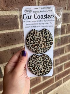 a package of car coasters in front of a brick wall with a hand holding it