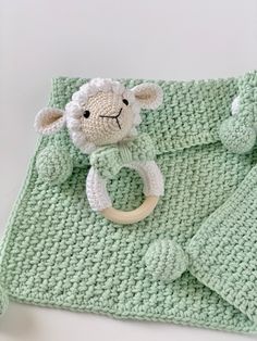 a green crocheted blanket with a sheep on it and a wooden ring in the middle