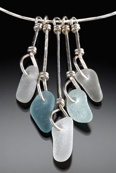 four sea glass pieces hanging from a silver necklace