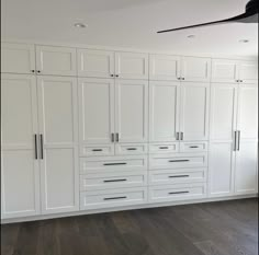 an empty room with white cabinets and wood floors