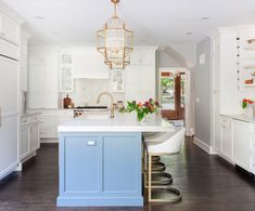 a kitchen with white cabinets and blue island