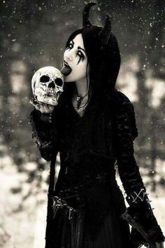 a woman dressed in black holding a skull