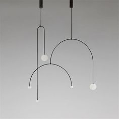 three lights hanging from the ceiling in front of a gray wall with no one on it