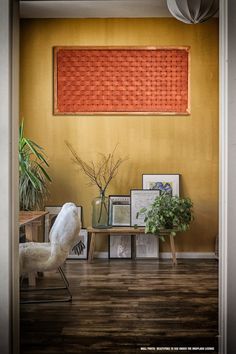 a room with a chair, table and pictures on the wall in front of it