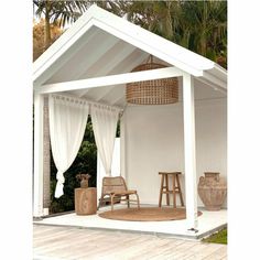 a white gazebo sitting on top of a wooden floor next to a lush green forest