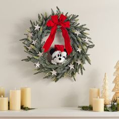 a christmas wreath with a mickey mouse on it next to candles and other holiday decorations