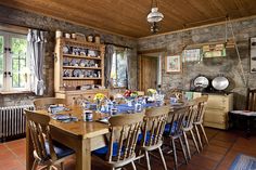 a dining room table set with blue place mats and plates on it, in front of a stone wall