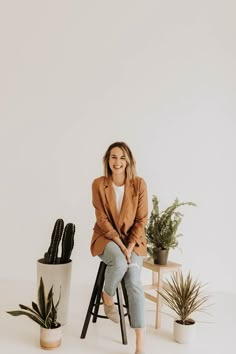 a woman sitting on top of a chair next to potted plants and a cactus