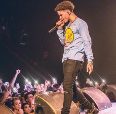 a man standing on top of a stage holding a microphone in front of a crowd