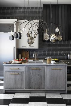 a kitchen with black and white checkered flooring, pots and pans hanging from the ceiling