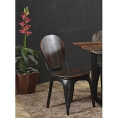 a wooden chair sitting on top of a carpeted floor next to a potted plant