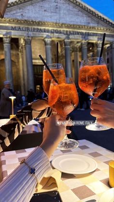 two people toasting with drinks in front of the roman forum at night, rome