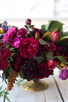 a vase filled with lots of purple and red flowers