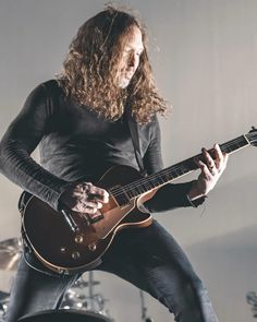 a man with long hair playing an electric guitar