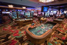 a casino room filled with lots of rouleets and slot machines on the floor