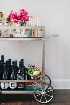 a cart filled with bottles and glasses on top of a hard wood floor