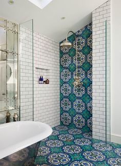 a bathroom with blue and white tiles on the floor, shower stall and bathtub