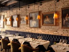 an empty restaurant with paintings on the wall and tables set up for two people to eat