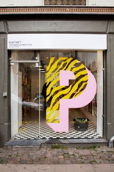 a store front with a large pink and yellow letter p on it's display window